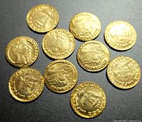 Photo showing 10 miniature gold plated replica coins spread out on a dark surface with clear embossed designs and the word MEXICANO.