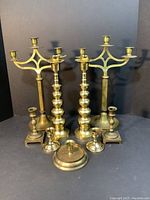 Front view of all nine brass candlesticks showing variety in size and design
