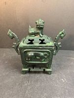 Front view of closed Shakyasimha incense burner with lion figure on lid, showing patina and ornate handles.