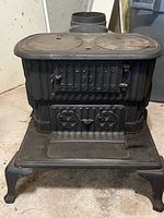Front view of the cast iron wood stove with front door embossed with 'COLUMBUS 99 FRANKLIN' and two vent knobs.