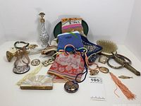 Wide view showing assortment of scarves, fabric box, ceramic perfume mister, umbrella handle, bracelets, pendants, vanity hairbrush, fan-shaped compact, and additional pieces.