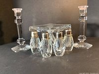 Full view of the two crystal candle holders and four cut crystal salt and pepper shakers arranged in front of the pedestal cake plate.