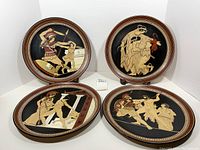 Four vintage Greek ceramic plates arranged on a display stand, showing all plates with mythological scenes and decorative borders.