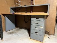 Front view of vintage shop workbench showing wooden top, metal frame, and five metal drawers on one side.