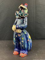 Full-length side view of astral themed clown figurine, showing star and planet painted clothing.