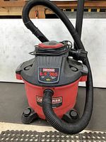 Front view of Craftsman shop vac showing attached hose, red and black colors, power cord wrapped on top.