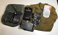 Photo of green aviator's kit bag with various black flight instruments and leather items laid on a white surface.