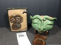 Both stoneware pieces displayed together: monkey plaque and face wall planter