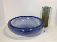 Lot showing blue glass bowl with thick rim and bulbous shape alongside tall cylindrical greenish vase.