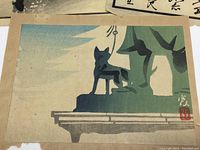 Close-up photo of a woodblock print showing a silhouette of a fox in front of bamboo reaching to the sky with a seal signature in red.