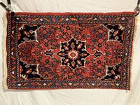 Full view of small oriental rug showing main design and border pattern with fringes at edges.
