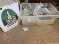Box containing a boxed church building and plastic bin with wrapped village components.