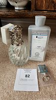 Full view of the glass Lampe Berger lamp, refill bottle, accessory piece, and auction tag.