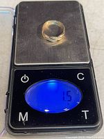 Photo of the 10KT gold ring placed on a digital scale showing the weight of 1.5 grams.