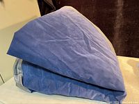 Folded blue and gray inflatable air mattress with velvety top and vinyl sides.