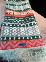 Close-up photo of the folded area rug showing geometric patterns, colors, and fringed edge