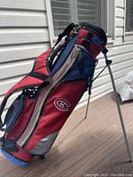 Full view of red, blue, and black golf bag with Montreal Canadiens logo and stand extended.