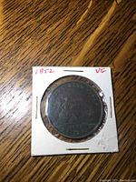 Obverse side of 1852 Quebec Bank penny token showing seated figure and inscriptions with VG grade noted on holder.