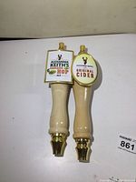 Two Alexander Keith's beer tap handles for Original Cider and Cascade Hop Ale, light wood finish with gold/brass accents.