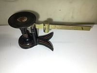 Side view of antique Fairbanks cast iron and brass weight scale showing base, arm, and weighing pan with visible wear and vintage label.