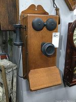Front view of the solid oak antique wall phone showcasing black metal bells, mouthpiece, and handset.