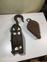 View of both metal pulleys together on white surface showing size difference and designs