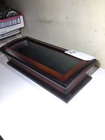 Side angle view of the wooden watch display case showing the convex glass top and wood finish.