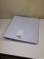 Closed white three-ring binder containing Coca Cola card sets