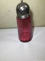 Front side view showing cranberry glass body and metal lid