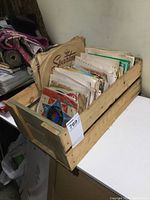 Wooden crate filled with vintage 45 RPM records and some 78s in paper sleeves, showing wear.