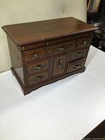 Closed view of the vintage jewelry box showing its wood finish and metal drawer pulls
