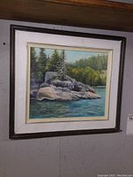 Full view of framed original oil painting depicting rocks and pine trees at Little Pigeon Bay, Lake Superior