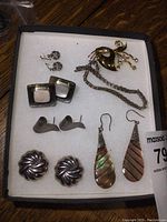 Full set of sterling silver jewelry in a box including earrings, bracelet, and brooch arranged flat on white padding.