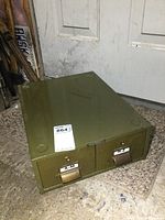 Side angle view of the vintage metal file box showing overall shape and olive green color.