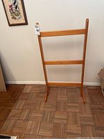 Wooden blanket rack standing against a wall with parquet floor