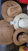 Four cowboy and cowgirl style hats grouped together, showing variety in color and weave pattern.