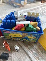 Blue plastic building blocks with animal figurines and assorted colorful blocks in branded container