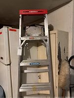 Front view of the Alberto Werner aluminum step ladder showing overall condition and the red top platform handle.