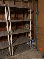 Photo of brown and beige plastic storage shelving unit with 5 shelves against a garage wall.
