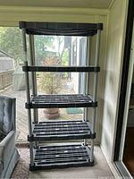 Front view of the 5-tier plastic shelving unit with black slatted shelves and grey supports.