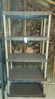 Front view of a gray plastic shelving unit with 5 levels and white supports, showing entire height and width.
