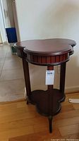Full view of side table showing clover-shaped top and three legs with feet caps.