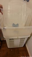 Large translucent plastic storage bin with ventilation slots at bottom, holding medium and small bins stacked on top inside.