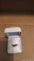 Ring displayed inside a white cushioned jewelry box showing the pink stone and gold band.