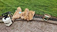 Photo of all items in the lot including the garden sprayer, coir liners, wireframe baskets, and Scotts seed spreader laid out on a stone patio with grass in the background