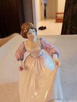 Front view showing the figurine's detailed face, dress, and pose holding a flower and lifting skirt.