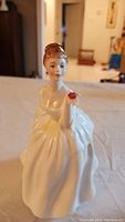 Front view of the Royal Doulton Flower of Love figurine showing the face, upper body and flower in hand.