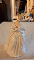 Front view showing full figurine with off shoulder dress and red bow detail on bodice.