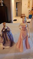 Photo showing both figurines, Nicole and Olivia, standing on a table with a room background.