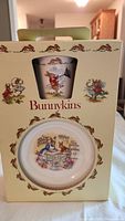 Front view of original packaging showing mug and cereal bowl through windows with Bunnykins branding and decorative rabbit borders.